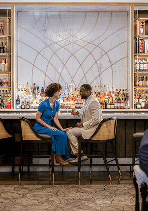 Dos huéspedes sentados en el bar del hotel uno frente al otro mientras charlan