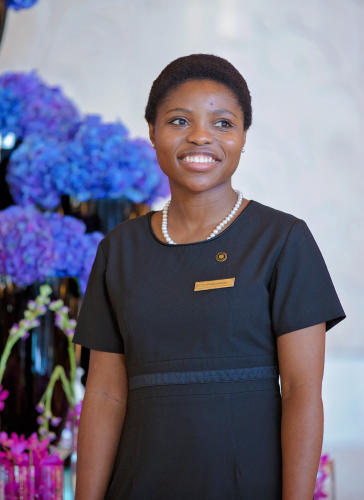 A female concierge in the UAE stands before vases of bright blue hydrangeas